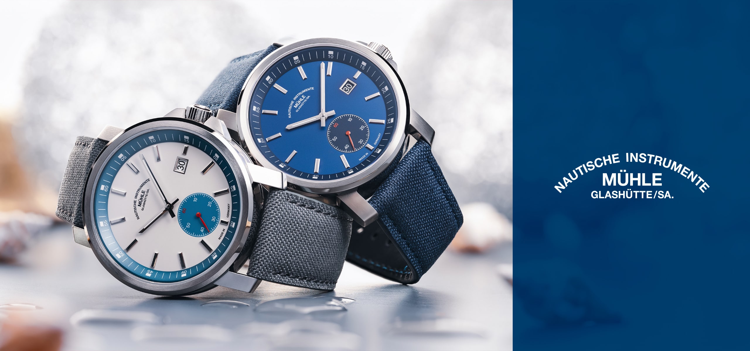 2025 © Mühle Glashütte Zwei Mühle Glashütte-Armbanduhren mit Stoffarmband werden vorgestellt: eine mit blauem Zifferblatt und Armband, die andere mit weißem Zifferblatt mit blauen Akzenten und grauem Armband. Das Logo der Mühle Glashütte ist rechts auf blauem Grund zu sehen.
