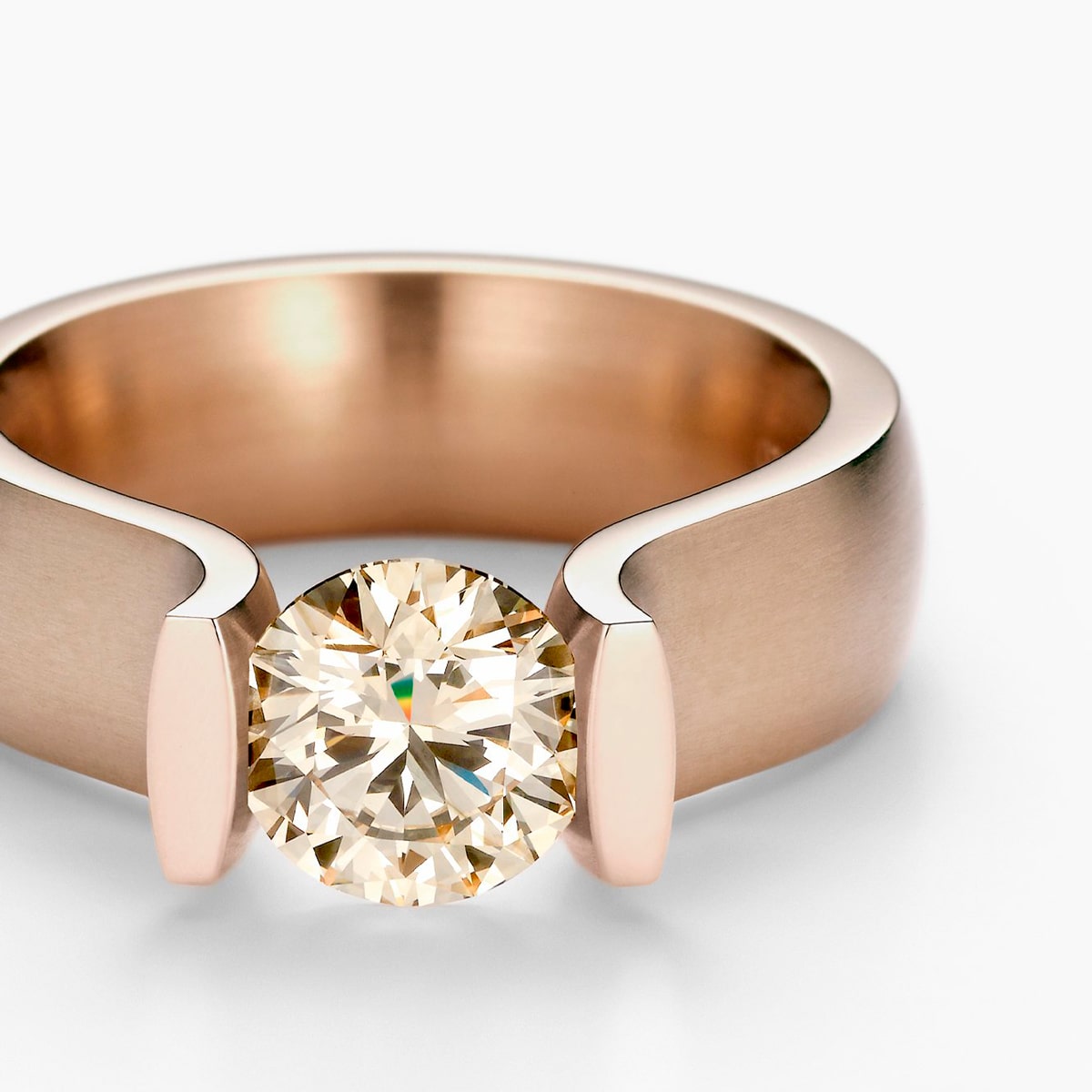 2025 © Niessing Eine Nahaufnahme eines Niessing Rings aus Roségold mit einem großen Diamanten im Rundschliff in einer modernen, offenen Fassung vor weißem Hintergrund.