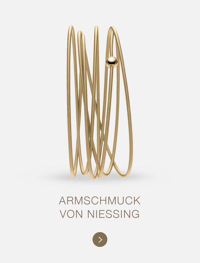 Ein modernes Goldarmband von Niessing mit mehreren sich überlappenden Schlaufen und einer einzelnen Goldperle auf hellem Grund. Der Text darunter lautet "ARMSCHMUCK VON NIESSING.