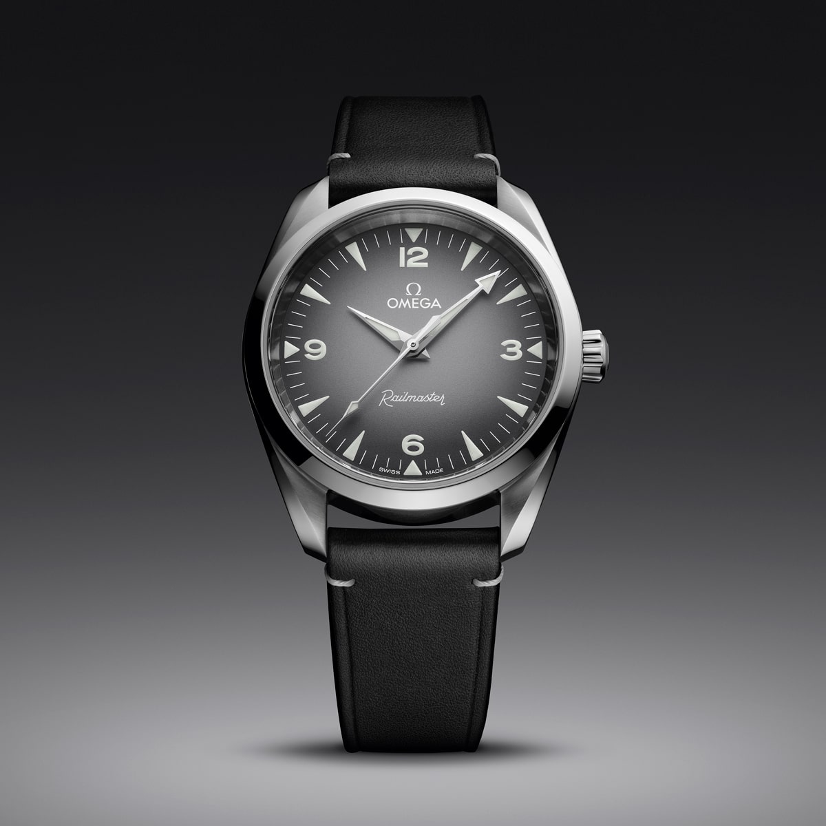 2025 © OMEGA Eine elegante Omega Railmaster-Armbanduhr, inspiriert von der Seamaster Heritage-Kollektion, mit schwarzem Lederarmband, dunkelgrauem Zifferblatt, silbernen Indexen und einem polierten Edelstahlgehäuse vor einem dunklen Hintergrund mit Farbverlauf.