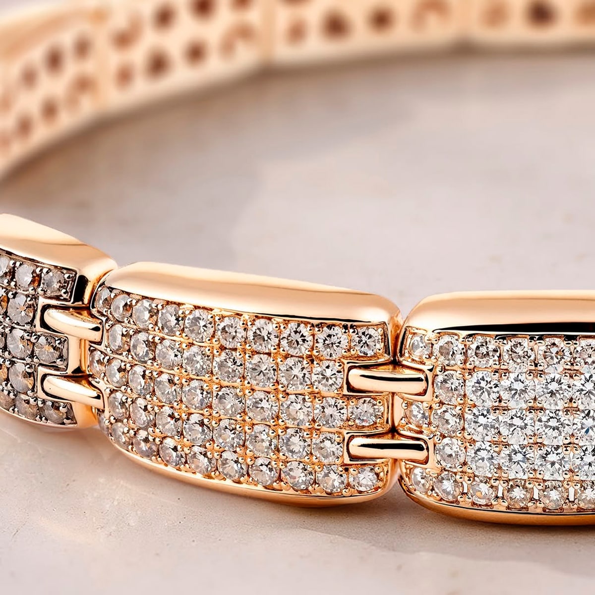 2025 © Al Coro Nahaufnahme eines Goldarmbands von Al Coro Armschmuck mit rechteckigen Gliedern, von denen jedes mit mehreren Reihen kleiner, funkelnder Diamanten besetzt ist, die elegant auf einer hellen Marmoroberfläche ruhen.