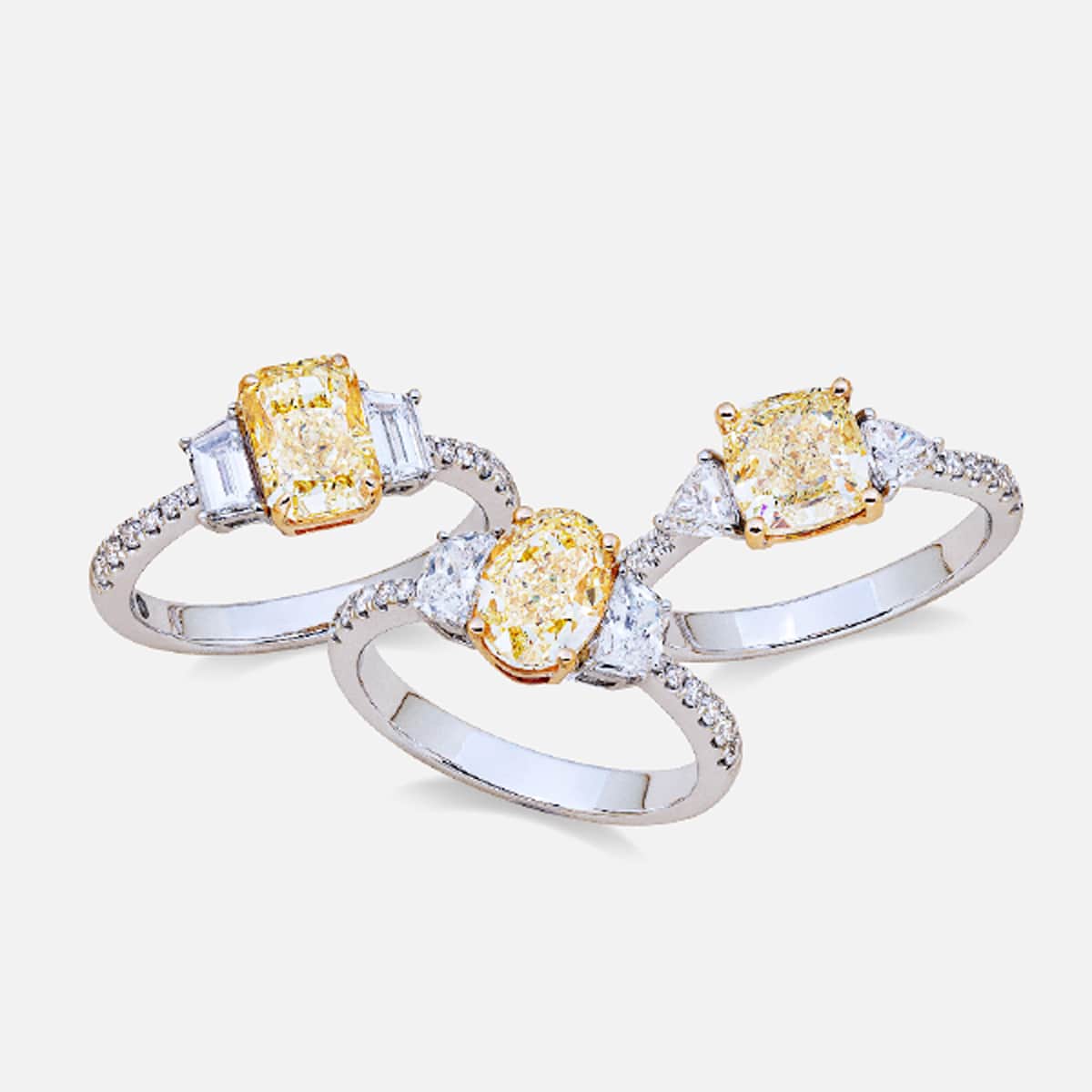 2025 © Diamond Group Drei Silberringe von DiamondGroup zeigen jeweils einen gelben Edelstein in der Mitte, der auf beiden Seiten von klaren weißen Steinen akzentuiert wird.