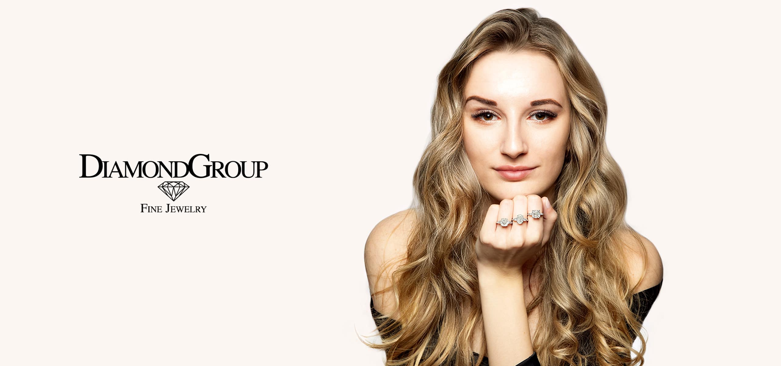 2025 © Diamond Group Eine Frau mit langen, gewellten blonden Haaren, die Ringe an ihren Fingern trägt, stützt ihr Kinn auf ihre Hände. Das Logo der DiamondGroup Fine Jewelry mit einem Diamantsymbol erscheint links auf einem hellen Hintergrund.