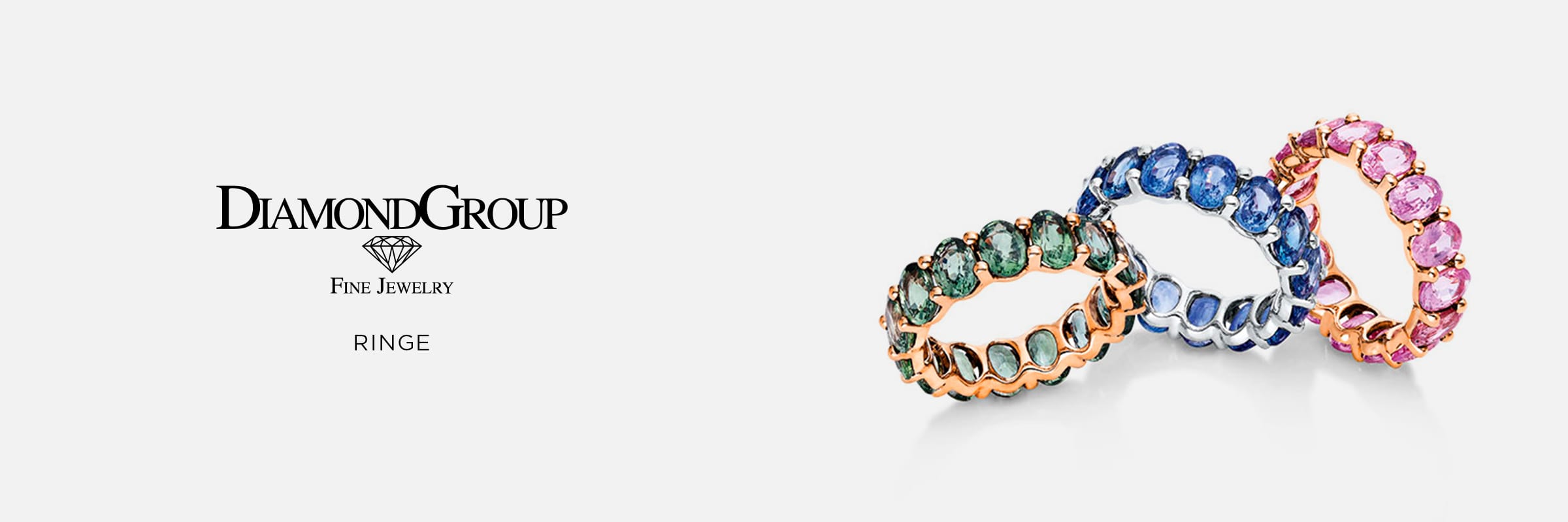 2025 © Diamond Group Drei Ewigkeitsringe mit Edelsteinen - ein grüner, ein blauer und ein rosafarbener - glänzen auf einer reflektierenden Oberfläche. Links erscheinen das Logo der DiamondGroup Ringe und der Text "Rings" in Schwarz auf weißem Hintergrund.