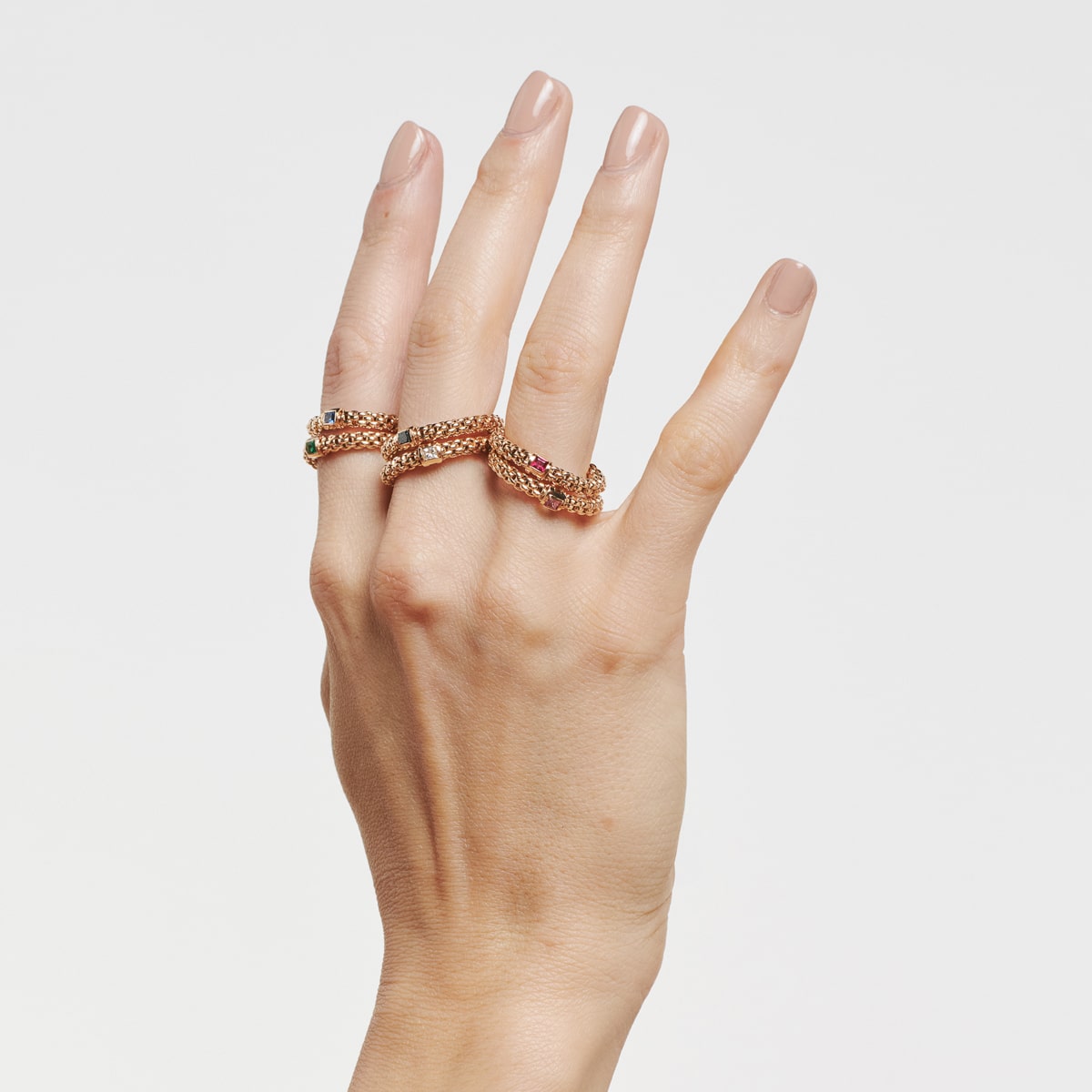 2025 © FOPE Eine Hand mit ordentlich manikürten Nägeln trägt auf Zeige- und Mittelfinger zwei FOPE Ringe, die jeweils mit bunten Edelsteinen besetzt sind, vor einem schlichten weißen Hintergrund.