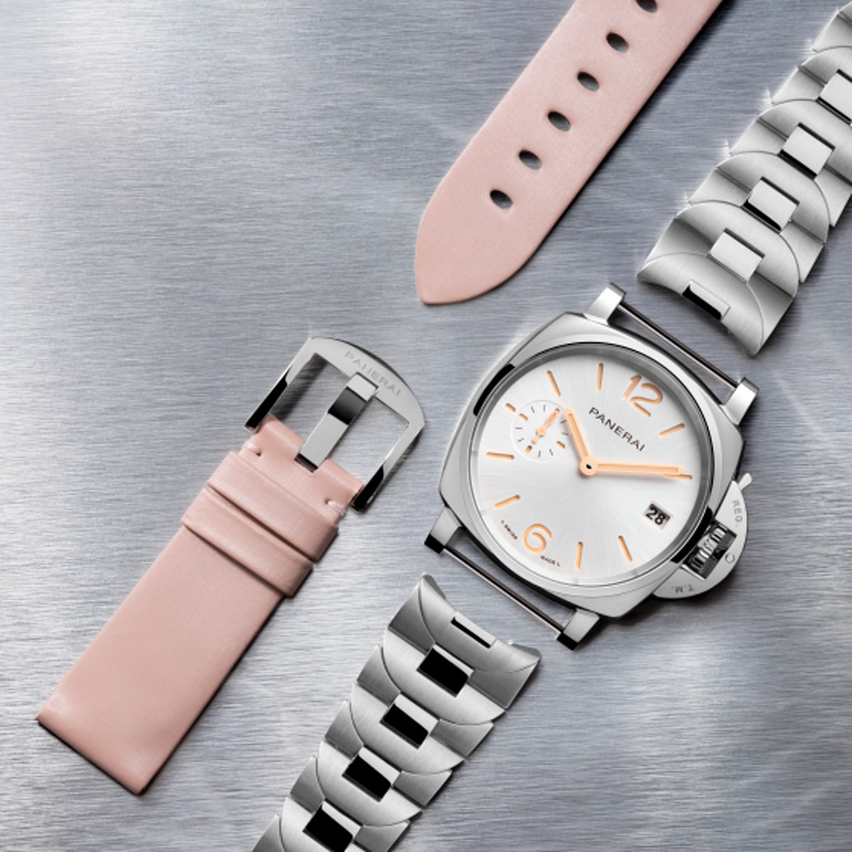 2025 © Panerai Eine luxuriöse Panerai Luminor Due Armbanduhr mit silbernem Metallband wird auf einer gebürsteten Metalloberfläche neben einem hellrosa Lederarmband präsentiert, das die austauschbaren Bandoptionen hervorhebt.