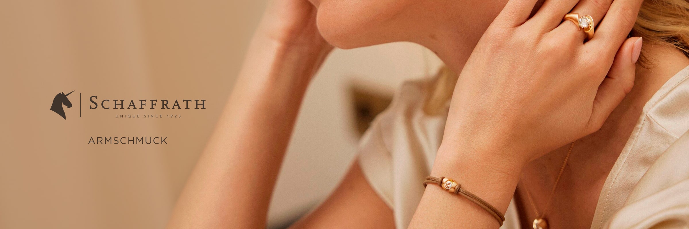 2025 © SCHAFFRATH Eine Frau, die einen goldenen SCHAFFRATH-Ring und ein dazu passendes goldenes Armband trägt, stützt ihr Kinn auf ihre Hand. Das Schaffrath-Logo und das Wort "Armschmuck" erscheinen auf der linken Seite des Bildes.