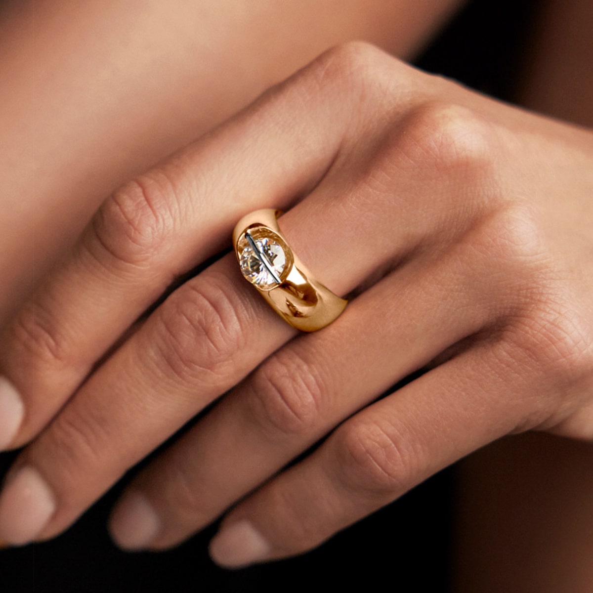2025 © SCHAFFRATH Nahaufnahme einer Hand, die einen SCHAFFRATH Ringe aus Gold mit einem markanten, runden Diamanten in der Mitte trägt. Die Hand hat sauber manikürte Nägel mit einem natürlichen Finish.