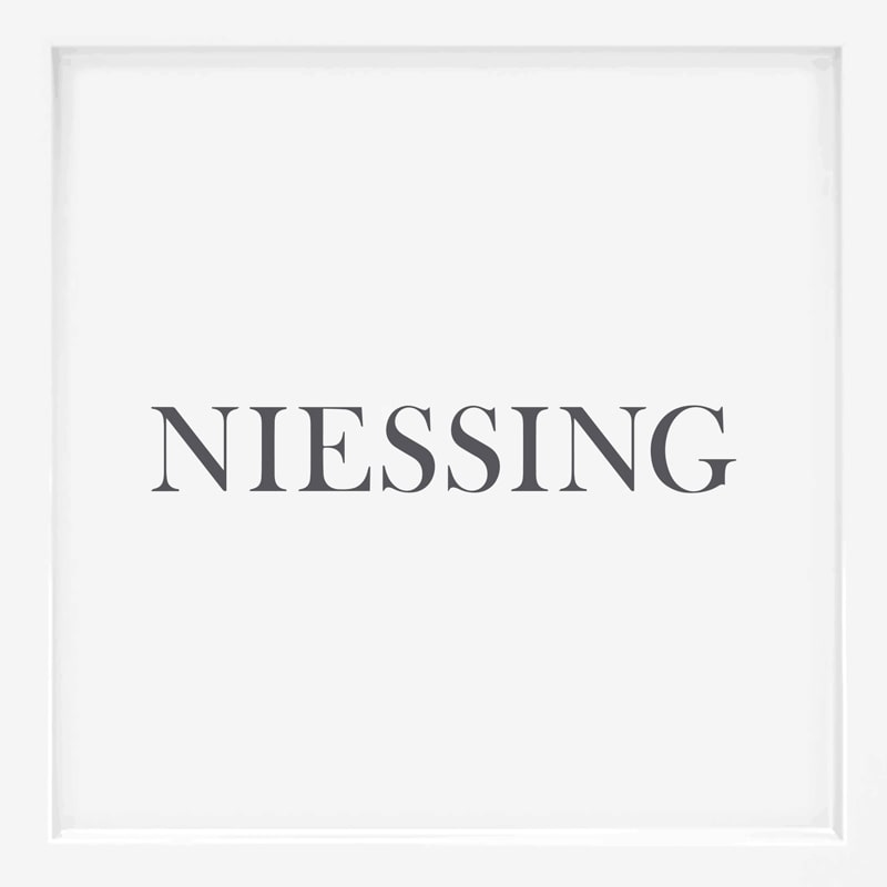 Das Wort "NIESSING", ein bekannter Name unter den Schmuckmarken, ist in grauen, großen Serifenbuchstaben auf einem schlichten weißen Hintergrund zentriert.