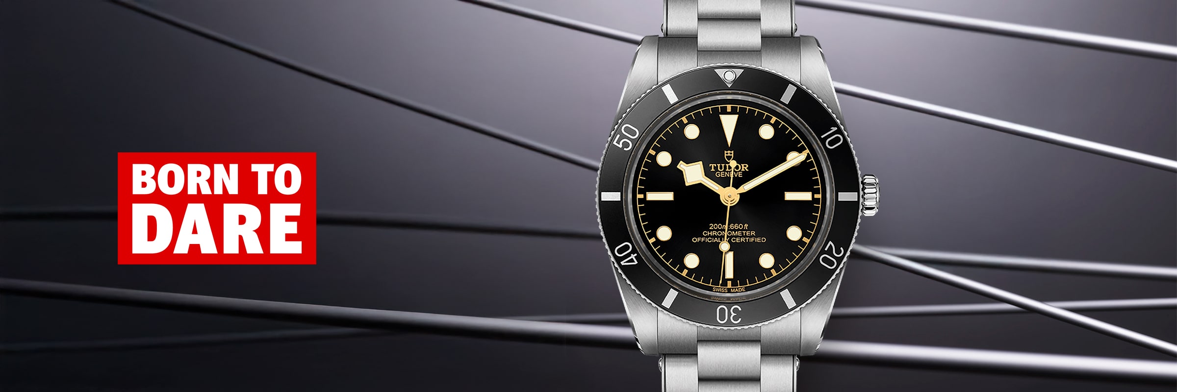 2025 © TUDOR Eine luxuriöse Tudor Black Bay 54 Armbanduhr mit schwarzem Zifferblatt und silbernem Band wird vor einem eleganten Hintergrund mit diagonalen Linien präsentiert. Auf der linken Seite steht in kräftigem Rot und Weiß "BORN TO DARE".
