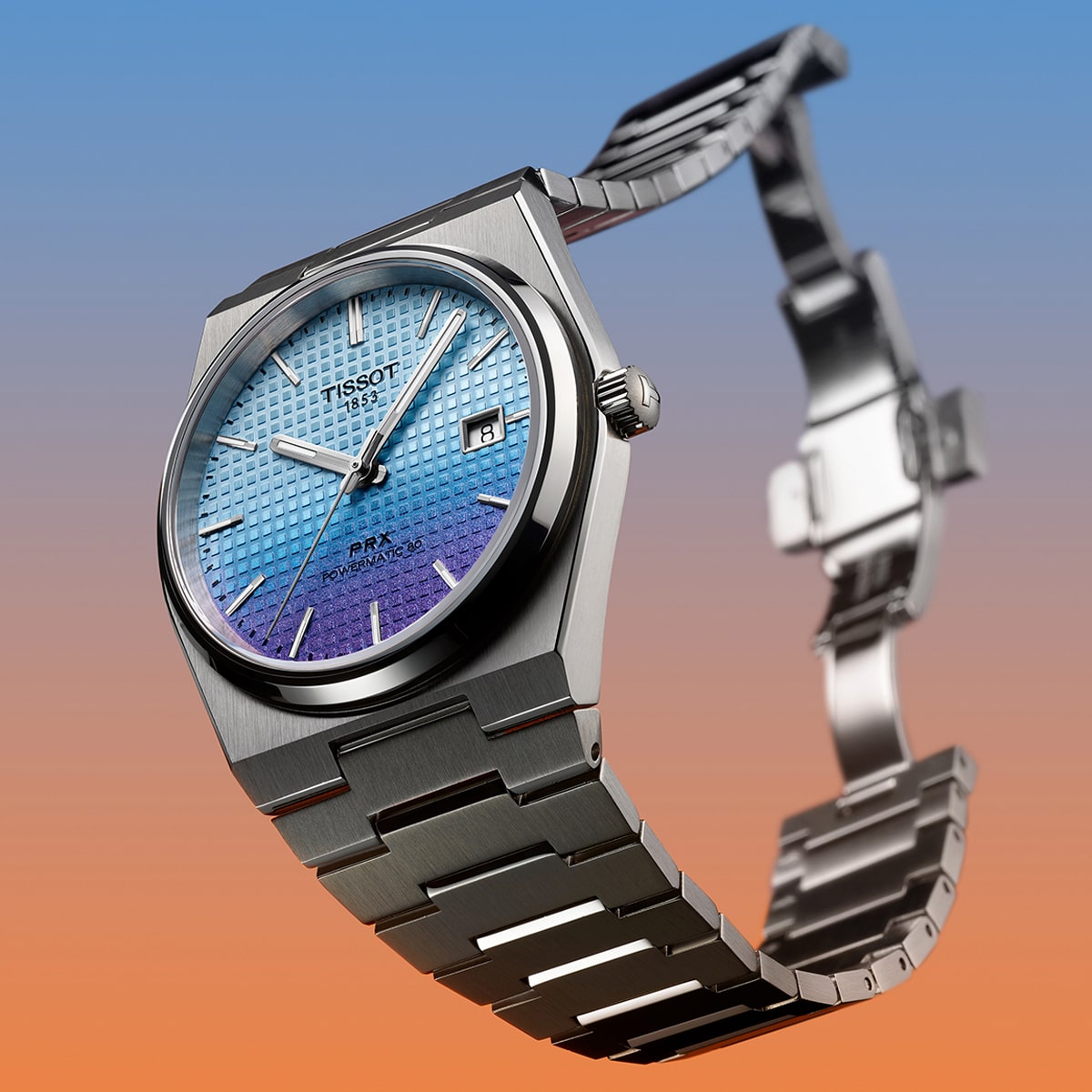 2025 © TISSOT Eine silberne Tissot PRX-Armbanduhr mit blauem, strukturiertem Zifferblatt, Datumsanzeige und Edelstahlarmband wird vor einem stilvollen Hintergrund mit blauem und orangefarbenem Farbverlauf präsentiert.
