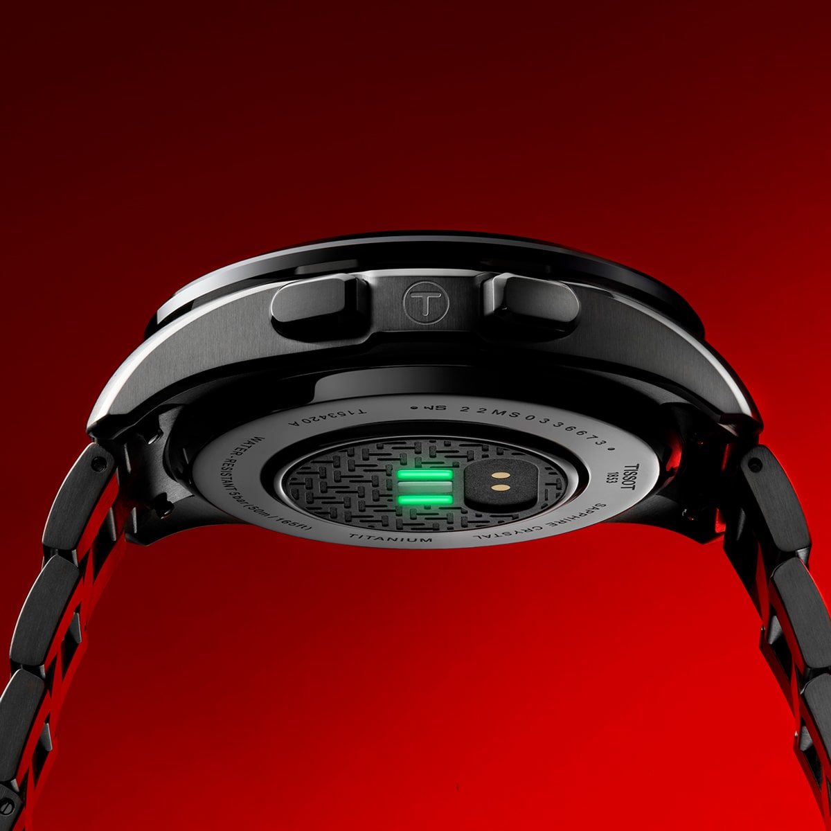 2025 © TISSOT Eine Nahaufnahme der Rückseite einer schwarzen Tissot T-Touch-Armbanduhr mit Metallband, die Sensoren und Gravurdetails vor einem roten Hintergrund zeigt.