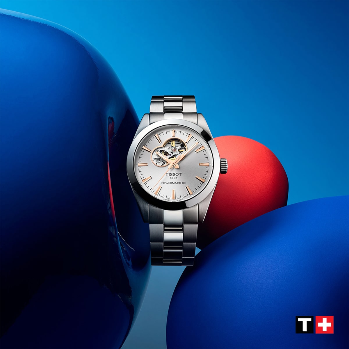 2025 © TISSOT Eine silberne Tissot Classic Armbanduhr wird vor einem leuchtend blauen und roten abstrakten Hintergrund dargestellt, mit dem Tissot-Logo in der unteren rechten Ecke.