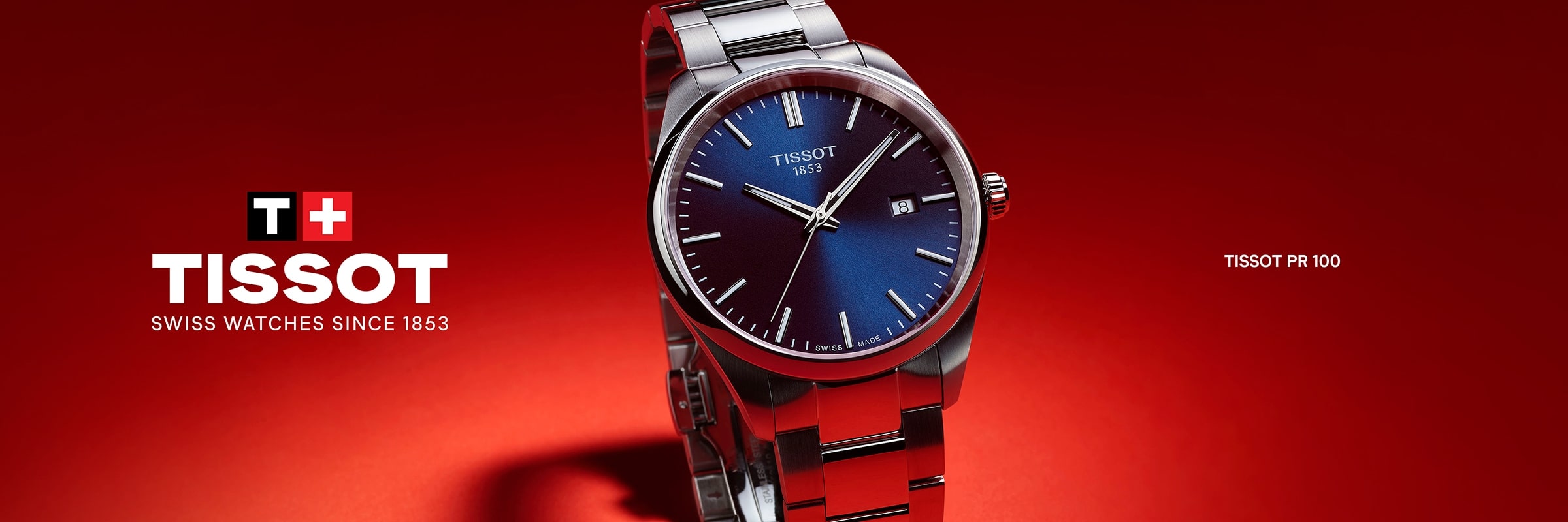 2025 © TISSOT Eine Tissot PR 100 Edelstahluhr mit blauem Zifferblatt ist auf rotem Hintergrund abgebildet, mit dem Tissot-Logo und dem Text SWISS WATCHES SINCE 1853".