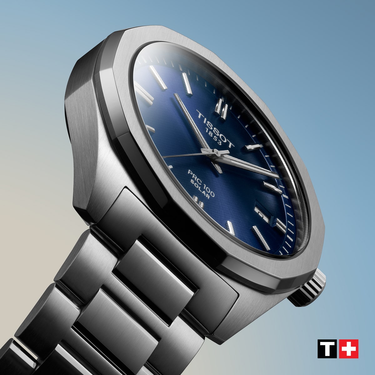2025 © TISSOT Nahaufnahme einer Tissot PRC 100 Solar Armbanduhr aus Edelstahl mit blauem Zifferblatt, silbernen Indexen und Metallarmband vor einem Hintergrund mit blauem und beigem Farbverlauf. Das Tissot-Logo erscheint in der unteren rechten Ecke.