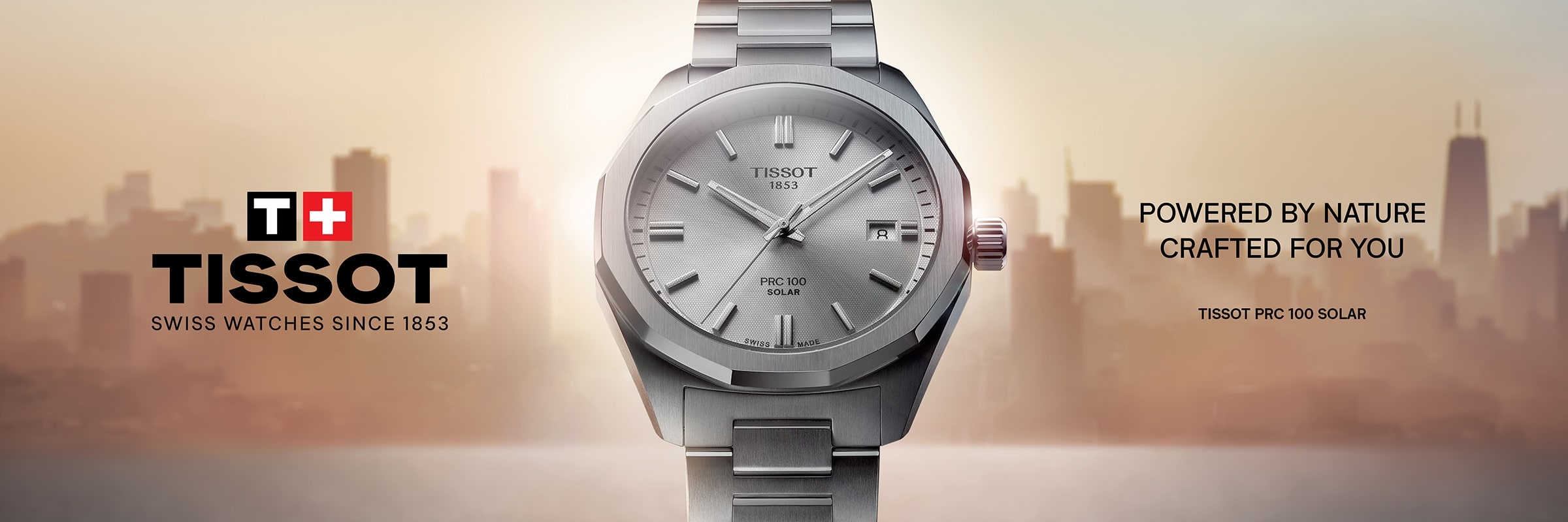 2025 © TISSOT Eine Tissot PRX 100 Solar Uhr mit silbernem Metallarmband und Zifferblatt ist vor dem Hintergrund einer Stadtsilhouette zentriert und hebt die PRC 100 Solar hervor. Das Tissot-Logo und der Slogan "Powered by nature, crafted for you" erscheinen neben der Uhr.