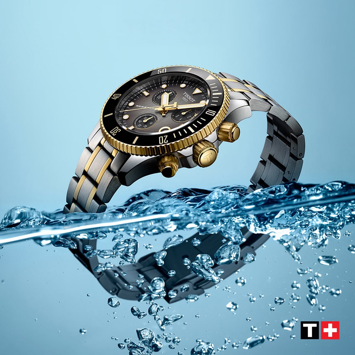 2025 © TISSOT Eine luxuriöse zweifarbige Tissot-Sportuhr mit schwarz-goldener Lünette ist teilweise in Wasser getaucht und von Spritzern umgeben. Der Hintergrund ist hellblau, mit einem rot-weißen Tissot-Logo in der unteren rechten Ecke.