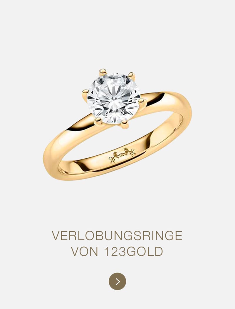 Ein goldener Verlobungsring mit einem großen runden Diamantsolitär ist auf einem hellen Hintergrund abgebildet. Darunter steht der Text "VERLOBUNGSRINGE VON 123GOLD", der die Eleganz und Qualität von 123GOLD hervorhebt, mit einer kleinen Pfeiltaste darunter.