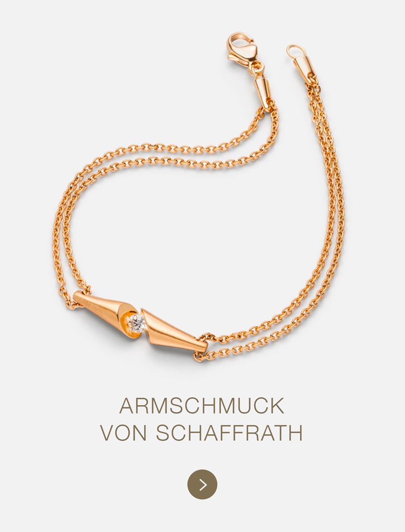 Ein zartes goldenes Kettenarmband von Schaffrath mit einem zentralen geometrischen Muster und einem kleinen Edelstein auf hellem Grund. Der Text darunter lautet: "ARMSCHMUCK VON SCHAFFRATH".
