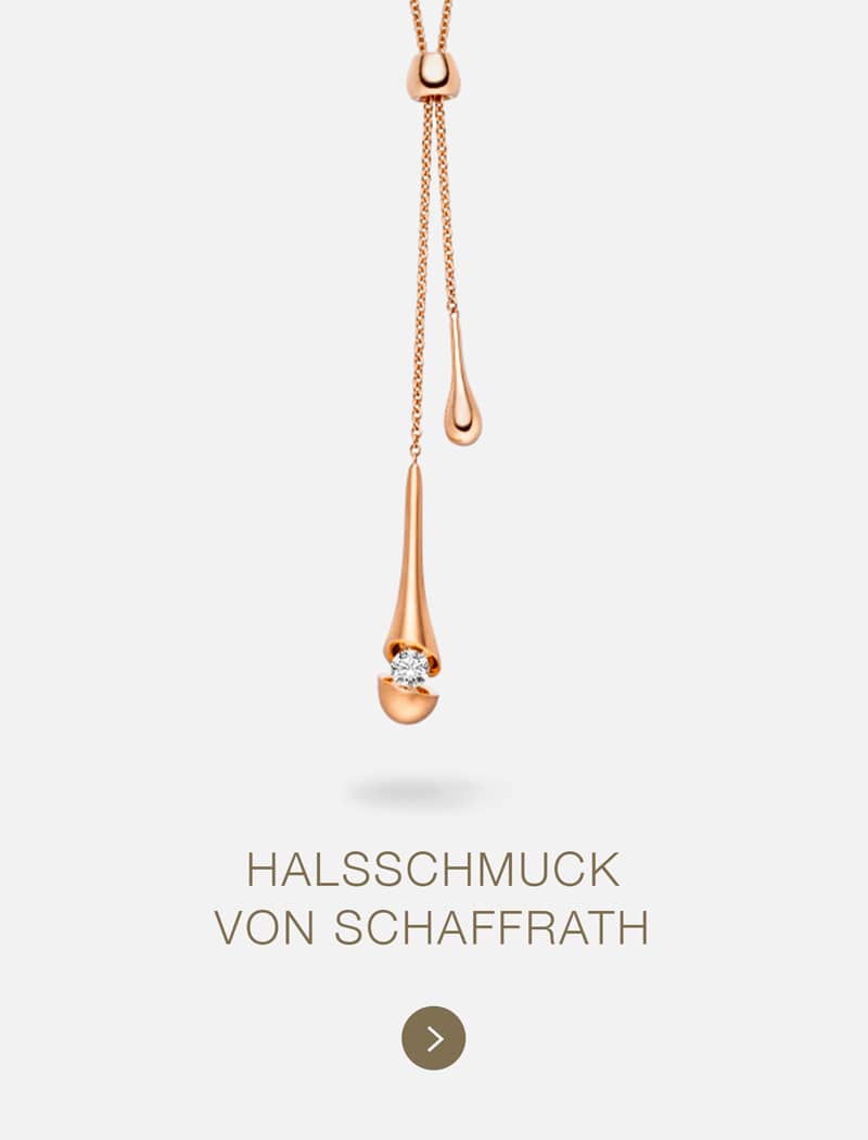 Eine goldene Halskette von Schaffrath mit zwei tropfenförmigen Anhängern, von denen einer mit einem Diamanten verziert ist, wird auf einem hellen Hintergrund gezeigt. Der Text darunter lautet "HALSSCHMUCK VON SCHAFFRATH".