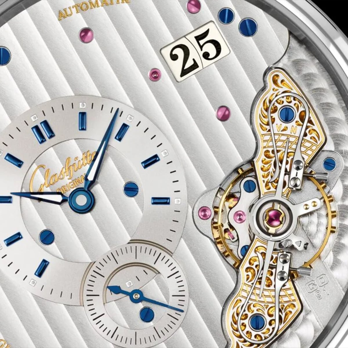 2025 © Glashütte Original Nahaufnahme eines luxuriösen Zifferblatts der Pano-Kollektion mit blauen Zeigern, einer großen Datumsanzeige, goldenen Zierrädern, rosafarbenen Edelsteinen und komplizierten mechanischen Details, die durch das teilweise offene Design sichtbar sind.