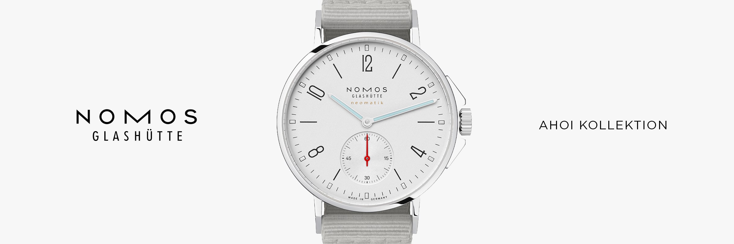 2025 © NOMOS GLASHÜTTE Minimalistische Anzeige mit der NOMOS Glashütte Ahoi: weißes Zifferblatt, blaue und rote Zeiger, graues Stoffarmband. Links "NOMOS GLASHÜTTE", rechts "AHOI KOLLEKTION" - das ist der zeitlose NOMOS Glashütte Ahoi-Stil.
