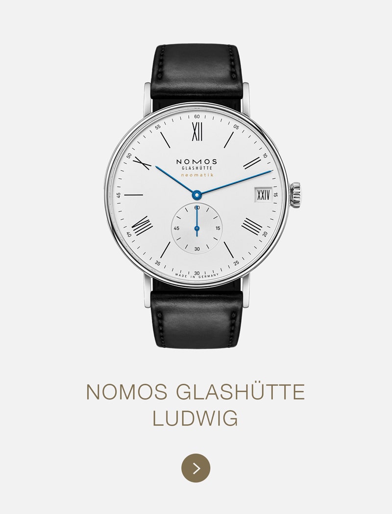 Eine NOMOS-Glashütte-Ludwig-Armbanduhr mit weißem Zifferblatt, schwarzen römischen Ziffern, blauen Zeigern, kleiner Sekunde und schwarzem Lederarmband ist auf hellem Grund abgebildet, darunter der Name NOMOS Glashütte.