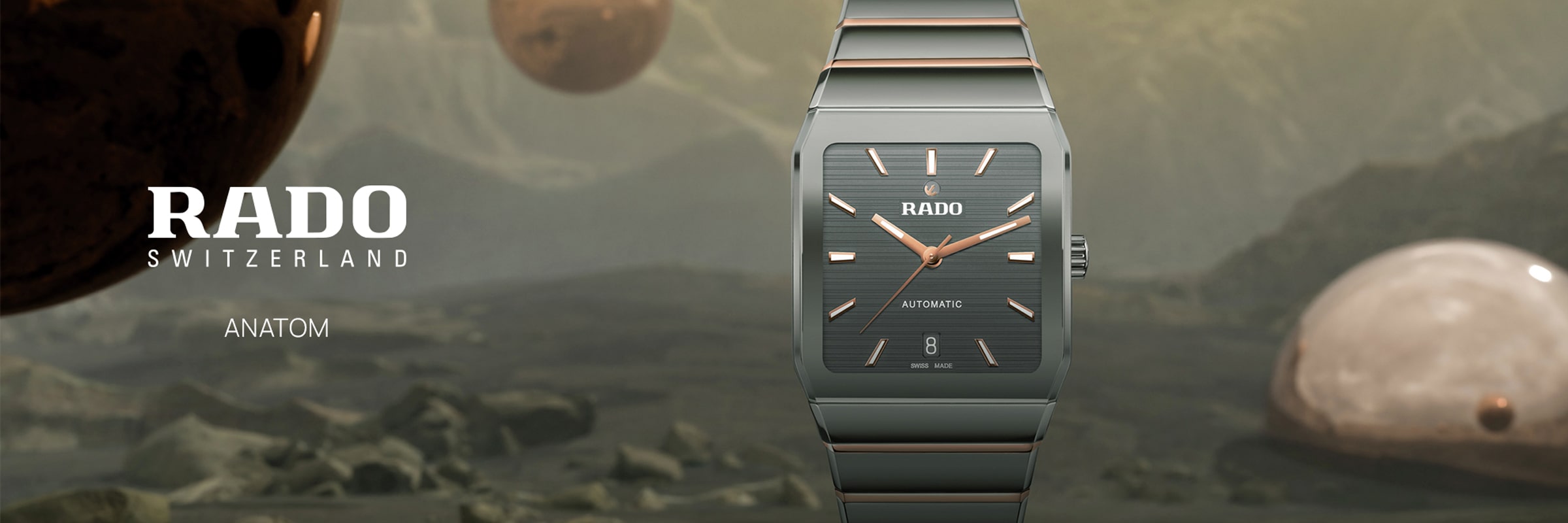 2025 © RADO Eine elegante Rado Anatom Uhr mit einem rechteckigen Zifferblatt in Schwarz und Roségold wird vor einer nebligen Landschaft mit großen, schwebenden Kugeln gezeigt. Der Text lautet: "RADO SCHWEIZ RADO ANATOM AUTOMATISCH.