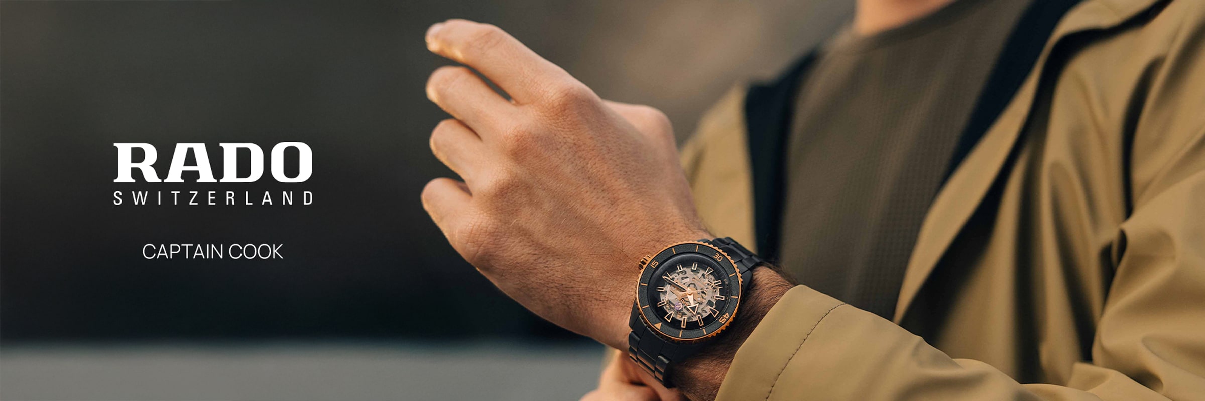 2025 © RADO Eine Person in einer hellbraunen Jacke stellt ihre Rado Captain Cook Armbanduhr am linken Handgelenk ein. Das Logo von Rado Switzerland und der Text "Captain Cook" sind auf der linken Seite des Bildes zu sehen.