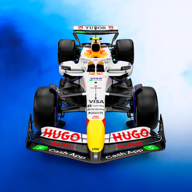 Ein Formel-1-Rennwagen in der Frontansicht mit prominenten Sponsorenlogos wie Hugo, Visa, Tudor und Red Bull vor einem Hintergrund mit blauem und weißem Farbverlauf.
