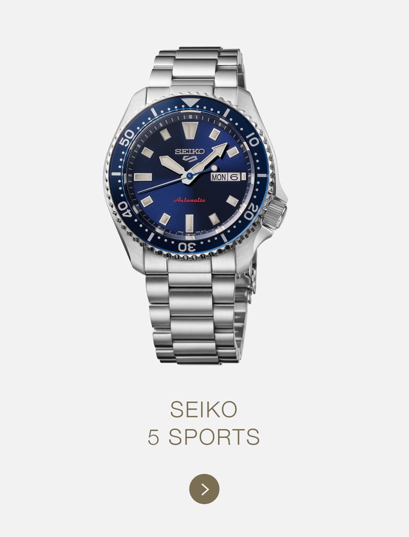 Eine Seiko 5 Sports Automatikuhr aus Edelstahl mit blauer Lünette und blauem Zifferblatt, silbernen Indexen und einem Datumsfenster auf weißem Hintergrund mit dem Text "SEIKO 5 SPORTS" darunter. Perfekt für Seiko-Liebhaber.