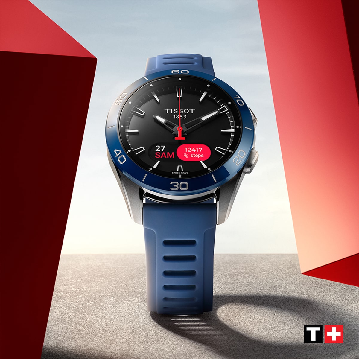 Eine Tissot T-Touch Smartwatch mit blauem Armband steht aufrecht zwischen zwei roten geometrischen Formen und zeigt auf ihrem Display die Uhrzeit, das Datum und die Schrittzahl an, mit dem Tissot-Logo in der unteren rechten Ecke.