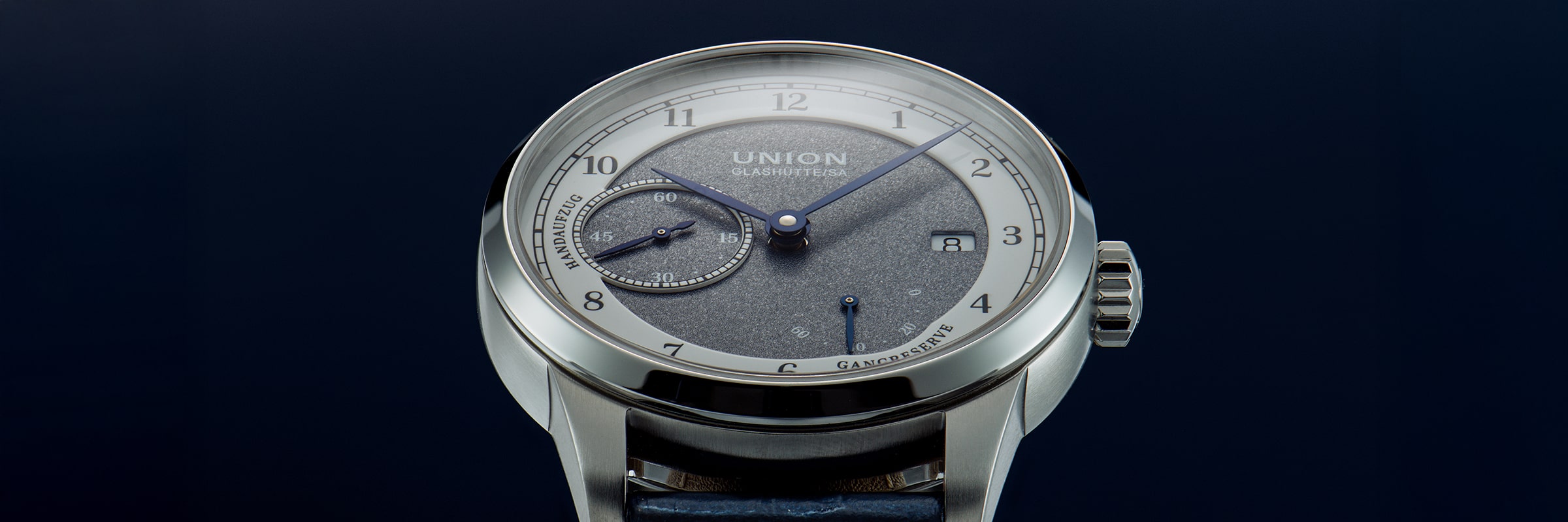 Nahaufnahme einer luxuriösen Union Glashütte 1893 Armbanduhr mit blauem und silbernem Zifferblatt, blauen Zeigern, einer kleinen Sekundenanzeige bei 9 Uhr und einem Datumsfenster bei 3 Uhr auf dunkelblauem Hintergrund.