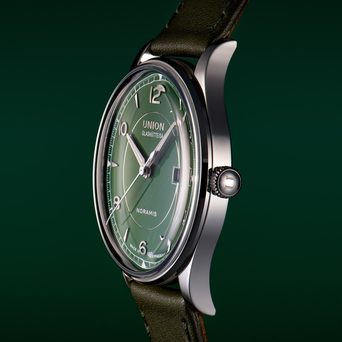 Eine Nahaufnahme einer Union Glashütte Noramis-Armbanduhr mit grünem Zifferblatt, silbernen Indexen und einem dunkelgrünen Lederarmband vor einem passenden dunkelgrünen Hintergrund der Union Glashütte Noramis.